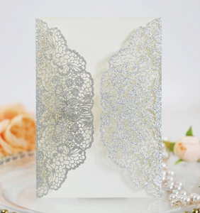 Detail view of laser-cut lace invitation card with silver glitter and soft floral accents