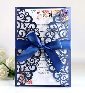 Detail of laser-cut navy blue wedding invitation with satin bow and floral inner card