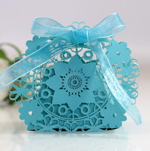 Detailed laser-cut floral pattern on light blue wedding favor box with organza ribbon