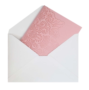 Detail of pink laser-cut wedding invitation with pearl texture and white envelope