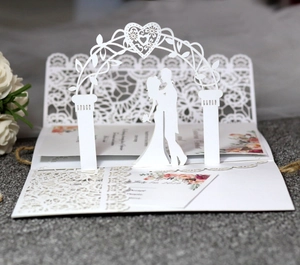 Detail of 3D laser cut wedding card showing romantic couple under a floral heart arch