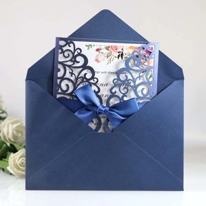 Detail of laser-cut navy blue wedding invitation with ribbon and floral insert