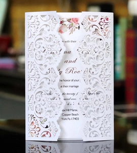 Detail of laser cut white wedding invitation with elegant hollow floral pattern design