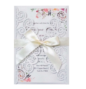 Détail d'invitation de mariage découpée au laser avec ruban beige et motif floral