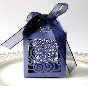 Macro view of purple laser-cut candy box featuring ornate scroll patterns and a blue ribbon