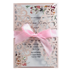 Detail of laser-cut rose gold wedding invitation with pink ribbon and floral insert card