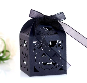 Macro shot of laser-cut Halloween pumpkin face candy box with black silk ribbon