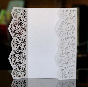 Macro view of white laser-cut wedding invitation with detailed lace floral patterns