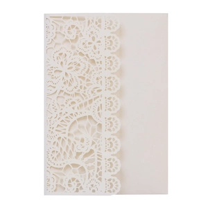 Macro detail of laser-cut lace floral pattern on white wedding invitation card