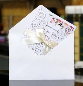 Détail d'invitation de mariage découpée au laser avec volutes, ruban et son enveloppe