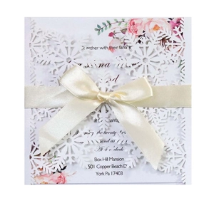 White laser-cut snowflake wedding invitation card with beige ribbon and floral inner sheet