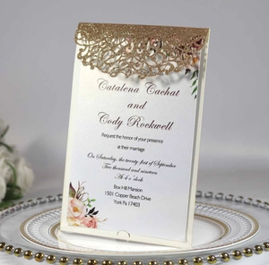 Macro shot of laser-cut glitter paper wedding invitation with floral inner card detail