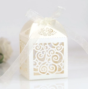 Elegant laser-cut heart pattern wedding favor box with cream ribbon bow on white background