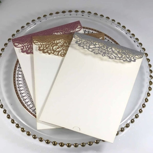 Detail of laser-cut glitter invitations in wine red, gold, and silver sparkling finish