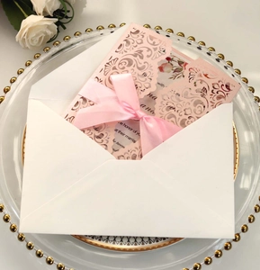 Elegant laser cut pink wedding invitation with a satin bow and floral inner card