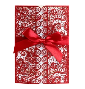 Detailed laser-cut wedding invitation with red glitter lace cover and satin bow decoration