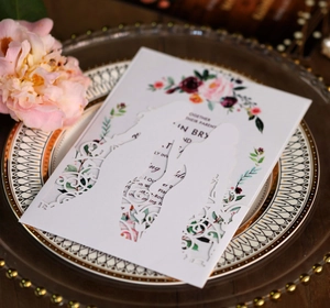 Detailed laser-cut wedding invitation featuring elegant white lace patterns and floral inserts