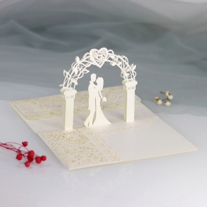 Detail of 3D laser-cut cream wedding card showing a couple kissing under a heart arch