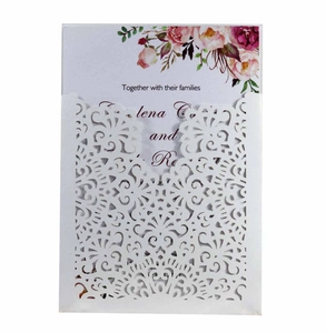 Macro shot of white laser-cut wedding invitation with floral inner card and floral patterns