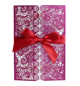 Detail of purple glitter lace laser cut wedding invitation with a red satin bow