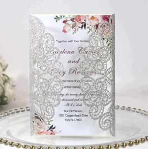 Détail d'invitation de mariage découpée au laser argentée avec paillettes et motif fleuri