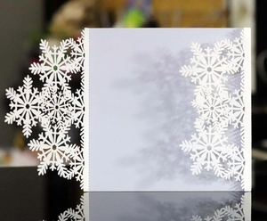 Detail of laser-cut white snowflake pattern on elegant wedding invitation card