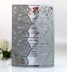 Macro shot of laser-cut silver sleeve and floral printed wedding invitation card