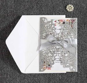 Detailed laser-cut silver glitter wedding invitation set with a soft grey satin ribbon bow