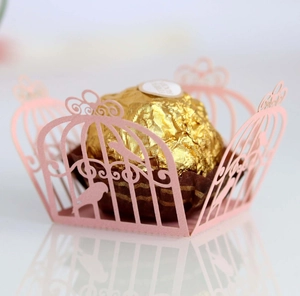 Pink laser-cut birdcage chocolate wrapper with intricate bird lace details on white surface