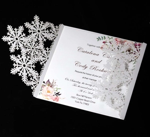Detail of laser-cut white snowflake wedding invitation with elegant floral inner card
