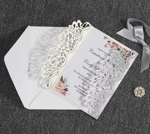 Detailed laser-cut cream wedding invitation with silver glitter band and floral inner page