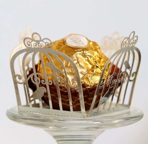 Detail of silver laser-cut birdcage pattern wrapper around a chocolate truffle