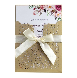 Detail of laser-cut wedding invitation with elegant satin bow and floral inner card