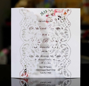 Detail of laser-cut wedding invitation cover with elegant white lace and floral inner card