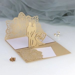 Makroansicht der goldenen lasergeschnittenen Hochzeitseinladung mit 3D-Herz-Detail