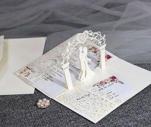 Macro shot of laser-cut lace edge and 3D floral arch on white wedding invitation card