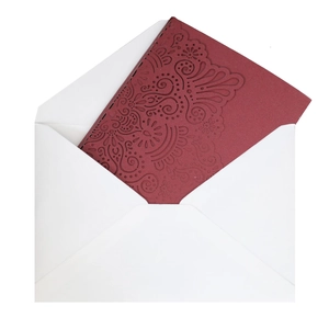 Detail of laser-cut burgundy invitation card with intricate mandala patterns and envelope