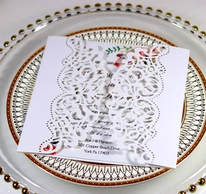 Detailed macro view of laser-cut lace pattern on elegant white wedding invitation cards