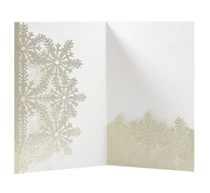 Macro detail of laser-cut snowflake patterns with silver glitter on white invitation card