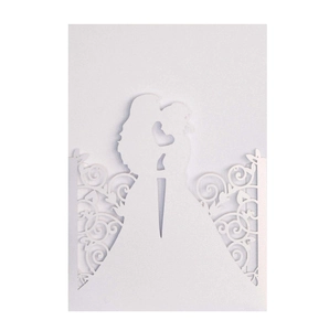 Macro shot of white laser-cut wedding card featuring a romantic kissing couple silhouette