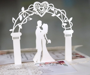 Close-up of 3D laser-cut wedding invitation featuring floral arch and couple silhouette