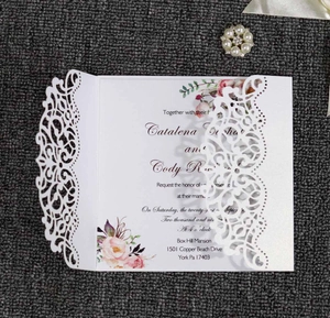 Macro view of laser-cut wedding invitation with hollow floral sleeve and elegant inner card