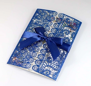 Detailed laser-cut dark blue lace wedding invitation with glitter finish and satin ribbon bow