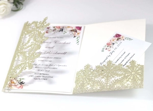 Macro detail of laser-cut snowflake glitter invite with floral inner card and RSVP set