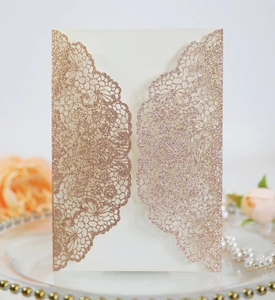 Close-up of laser-cut lace invitation card in rose gold glitter finish for weddings