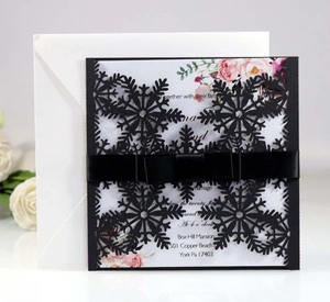 Detailed laser-cut black snowflake wedding invitation with silk bow and floral insert