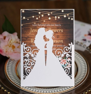 Intricate laser-cut wedding invitation featuring a couple silhouette and vintage wood grain card