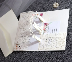 Detail of 3D laser-cut wedding invitation with lace cutout and pop-up couple arch decoration