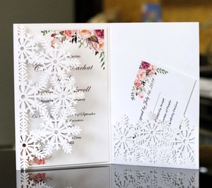 Detailed laser cut white snowflake invitation cover with floral inner card and RSVP