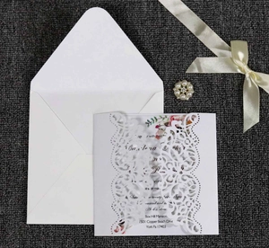 Close-up of laser-cut wedding invitation set with elegant floral inner card and envelope